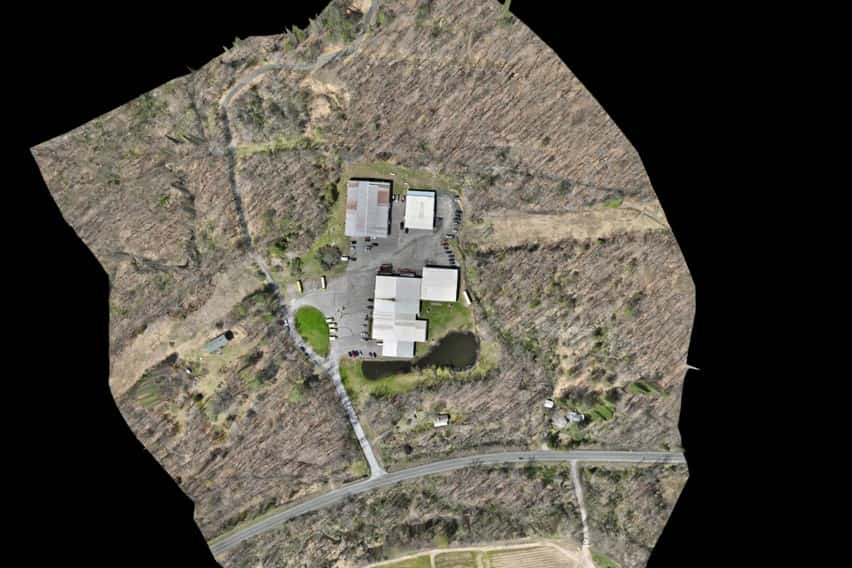 Orthomosaic aerial map of a site with buildings, driveway and pond, surrounded by woodland