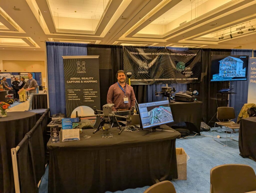 Harkin team member beside a drone at a trade show booth with monitor and banners
